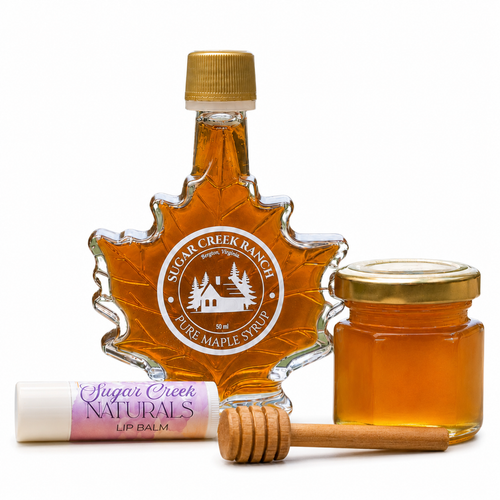 Maple syrup bottle, lip balm, wooden dauber, and honey jar with 'Sugar Creek Ranch' branding on a white background.